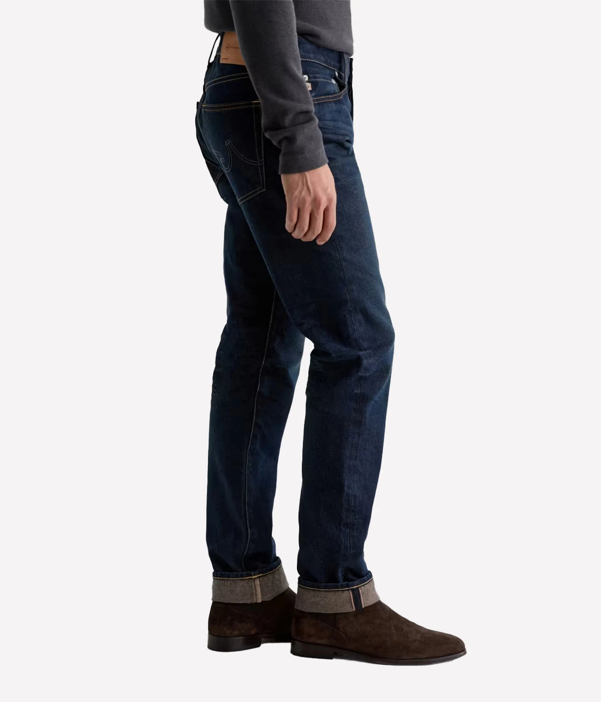 Man wearing AG Tellis Selvage Jean in 3 Years Out Of The Blue with brown suede boots, side view