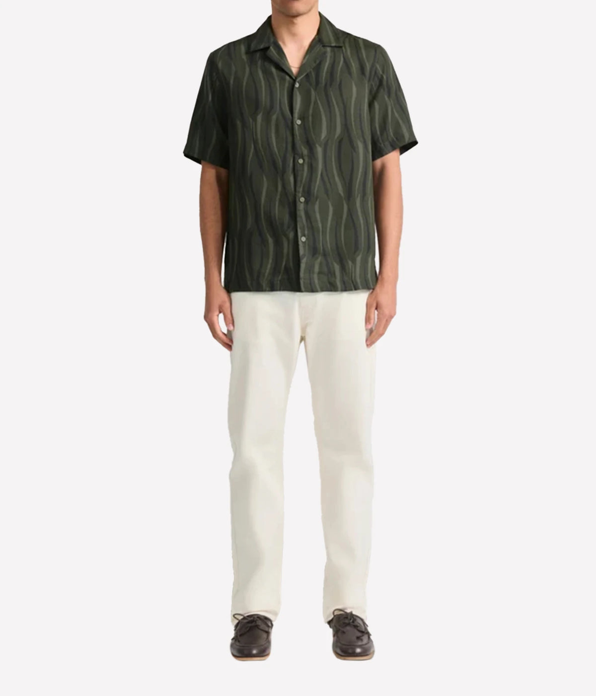 A man wearing a Frescobol Carioca Roberto Short Sleeve Linen-Blend Shirt in Cove Green with a wavy vertical stripe pattern, paired with off-white trousers and dark brown shoes, standing against a plain white background.
