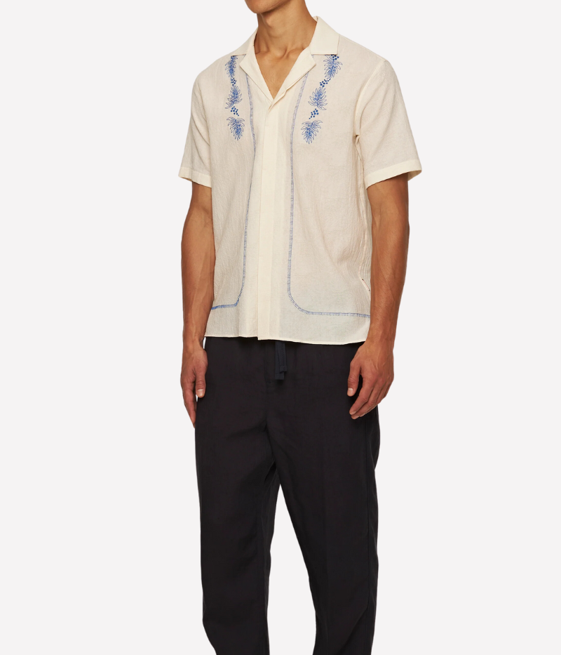 White Sands Orlebar Brown Maitan Anthinos Shirt with Capri collar, concealed button placket, and intricate blue Grecian-inspired embroidery along the placket and hem. Made from lightweight Italian-woven cotton with side hem splits and imitation mother-of-pearl buttons