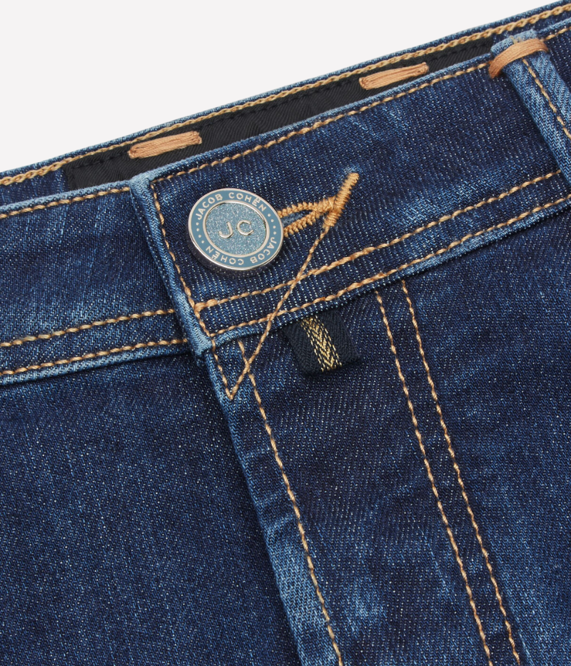 Jacob Cohën's Bard 5 Pocket Jeans from the exclusive Black Label Diamond Edition, crafted from dark blue super-stretch denim with a soft enzyme-washed finish. Features include subtle abrasions, logo embroidery on the coin pocket, a removable black calf hair patch with a gold-tone logo and diamond dust JC motif, and a light gold-tone button with cobalt-blue enamelled edges and diamond dust.