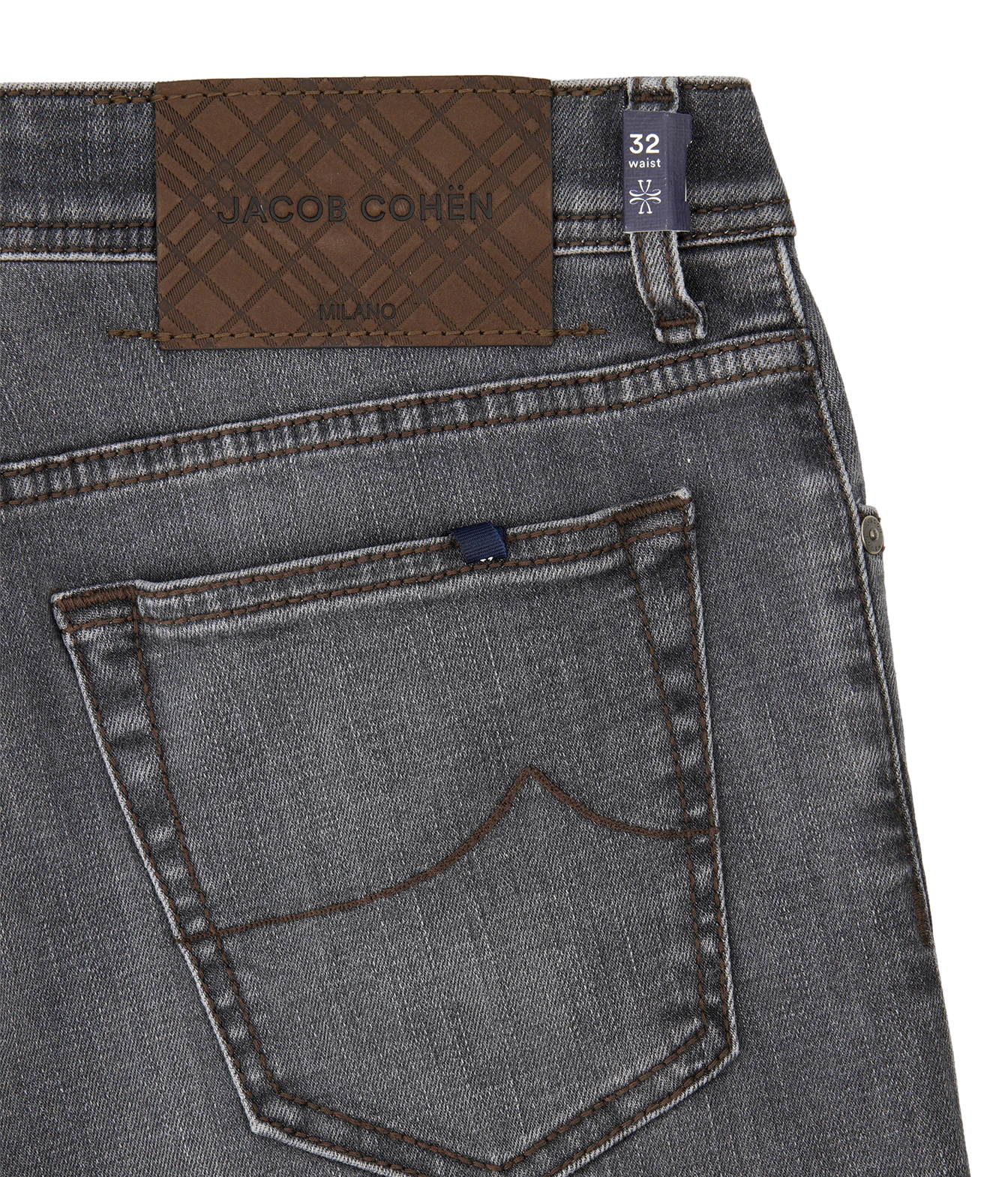 Close-up of the back waistband and pocket area of gray denim jeans, showing a brown jacquard brand patch that reads JACQUE COHEN MONO, a dark blue size tab marked 32, and contrast stitching.