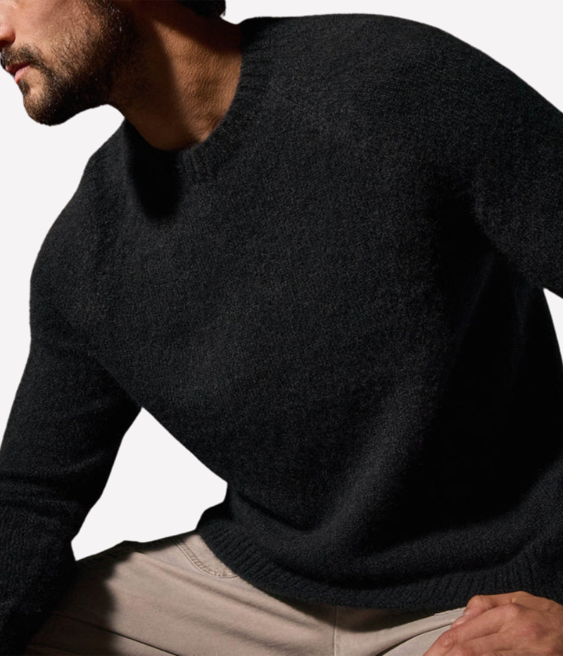 A lightweight, true black cashmere crewneck sweater featuring ribbed detailing at the neckline, cuffs, and hem for a classic and polished appearance.