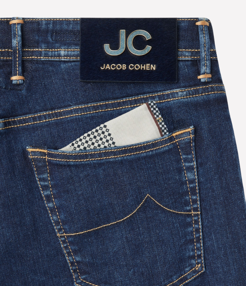 Jacob Cohën's Bard 5 Pocket Jeans from the exclusive Black Label Diamond Edition, crafted from dark blue super-stretch denim with a soft enzyme-washed finish. Features include subtle abrasions, logo embroidery on the coin pocket, a removable black calf hair patch with a gold-tone logo and diamond dust JC motif, and a light gold-tone button with cobalt-blue enamelled edges and diamond dust.