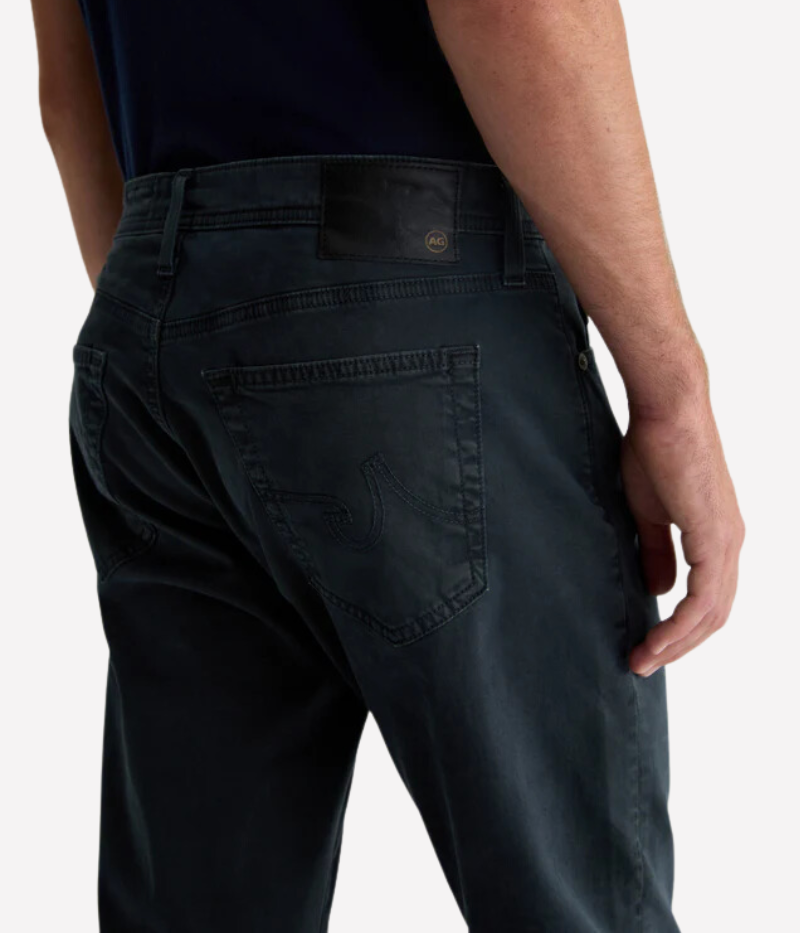 AG's Everett slim-straight men's pants in dark grey, crafted from 8.4 oz. Sueded Stretch Sateen from Italy. Featuring a mid-rise waist and a straight fit relaxed from hip to knee with a slight taper at the leg opening. Detailed measurements include a 10 1/4" front rise, 16 1/2" knee opening, 15" bottom opening, and 34" inseam.