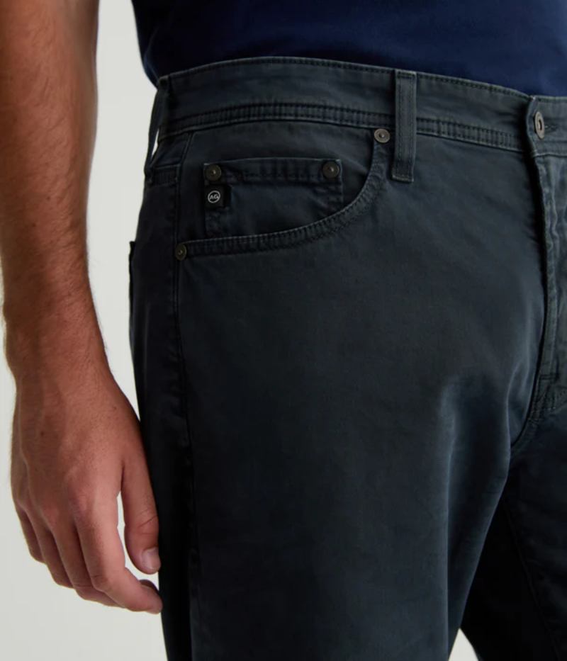 AG's Everett slim-straight men's pants in dark grey, crafted from 8.4 oz. Sueded Stretch Sateen from Italy. Featuring a mid-rise waist and a straight fit relaxed from hip to knee with a slight taper at the leg opening. Detailed measurements include a 10 1/4" front rise, 16 1/2" knee opening, 15" bottom opening, and 34" inseam.