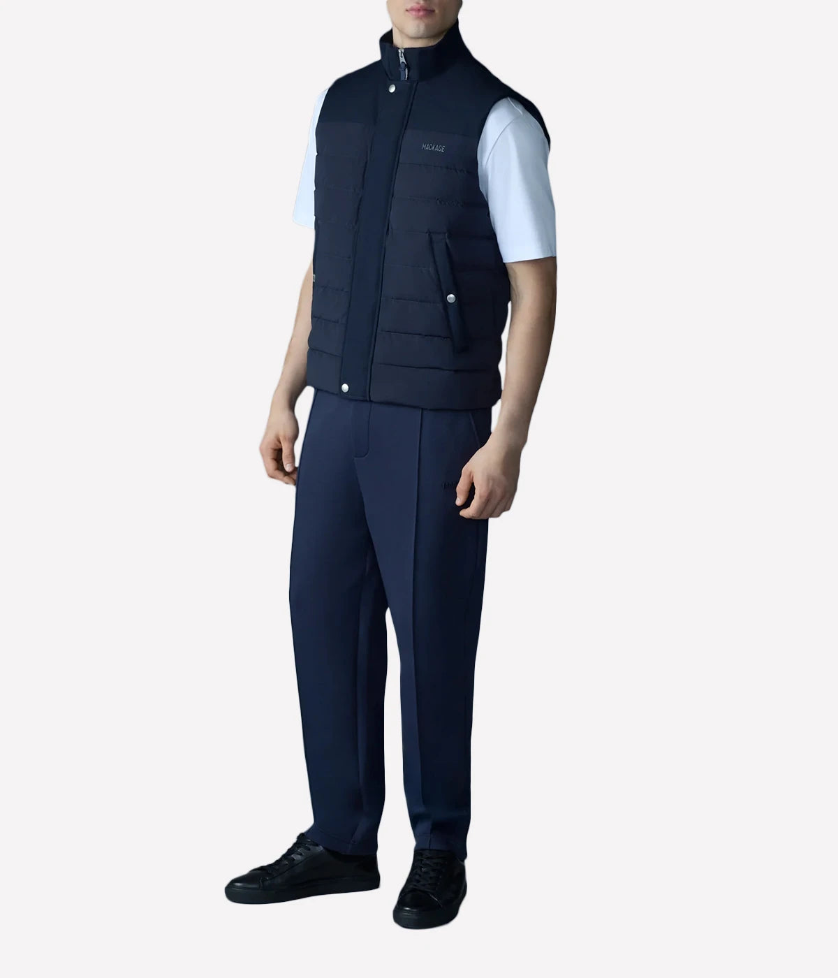 Quilted down vest with stretch nylon and twill panels, ribbed collar, and snap-secured pockets, designed for lightweight warmth and layering.