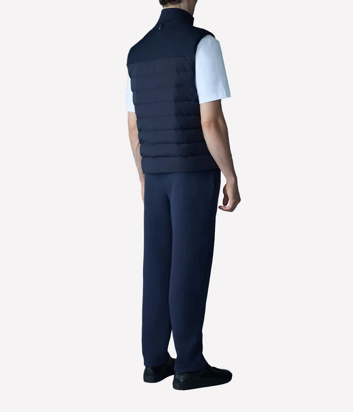 Quilted down vest with stretch nylon and twill panels, ribbed collar, and snap-secured pockets, designed for lightweight warmth and layering.