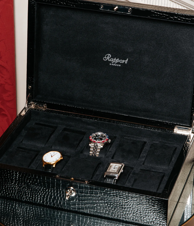 The Brompton Watch Box is meticulously handcrafted from solid wood and wrapped in luxurious black crocodile-pattern leather. Designed to hold up to ten watches, it features a plush suede-lined interior and adjustable cushions to securely fit timepieces of all sizes. A sophisticated storage solution for protecting and displaying your watch collection.