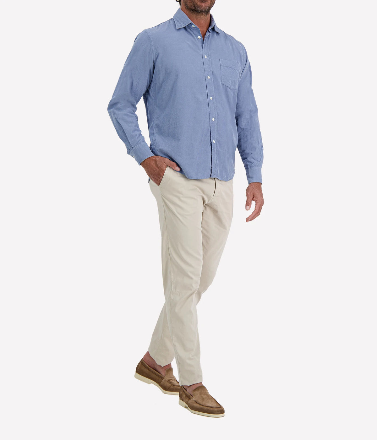 Man wearing Hartford Paul Fine Corduroy Shirt in Chambray Blue with stone chinos and brown suede shoes, angled front view with hand in pocket