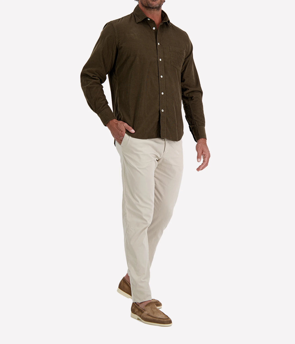 Man wearing Hartford Paul Fine Corduroy Shirt in Olive with stone chinos and brown suede shoes, angled front view with hand in pocket