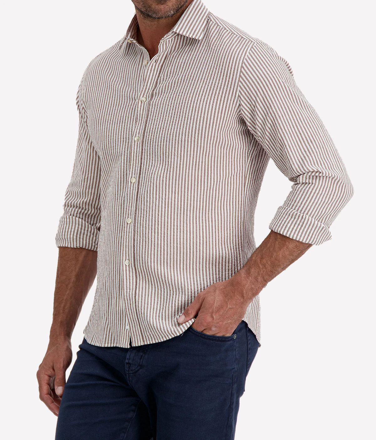 Man wearing Ingram Slim Fit Shirt in Seersucker Brown & White Stripe with indigo jeans, cropped angled front view with hand in pocket
