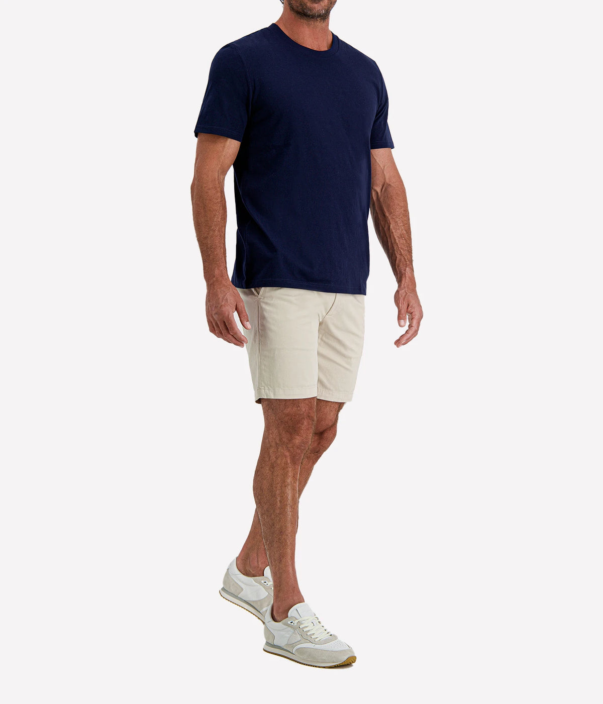 Man wearing Calexico Man Jamie Tee in Navy with stone shorts and white sneakers, three-quarter view
