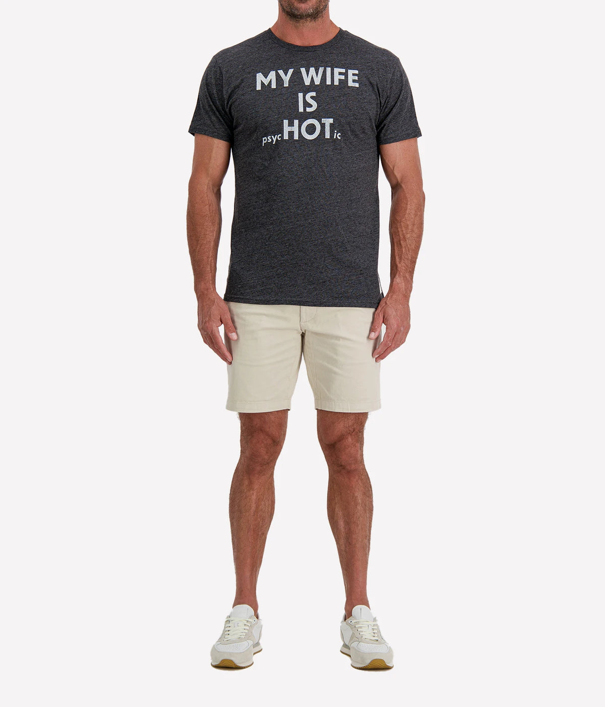 Man wearing Retro Brand My Wife Is Psychotic Tee in Black with stone shorts and white sneakers, full-length front view