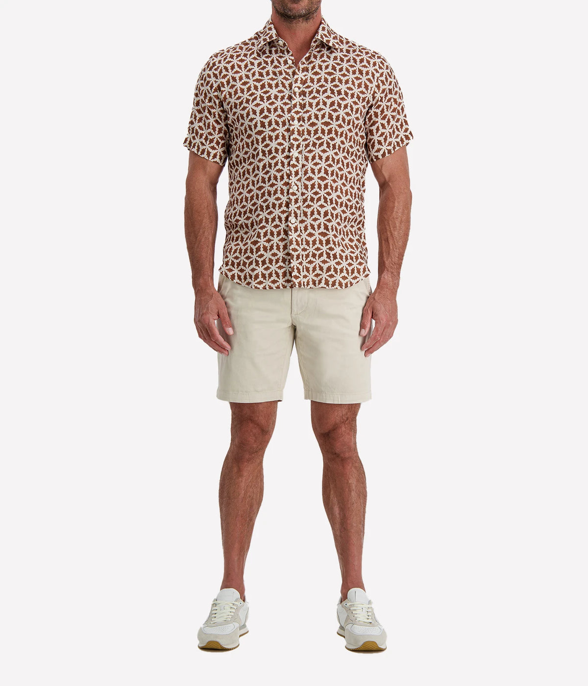 Man wearing Osvaldo Trucchi Linen Short Sleeve Shirt in Brown Geo Star Print with stone shorts and white sneakers, full-length front view