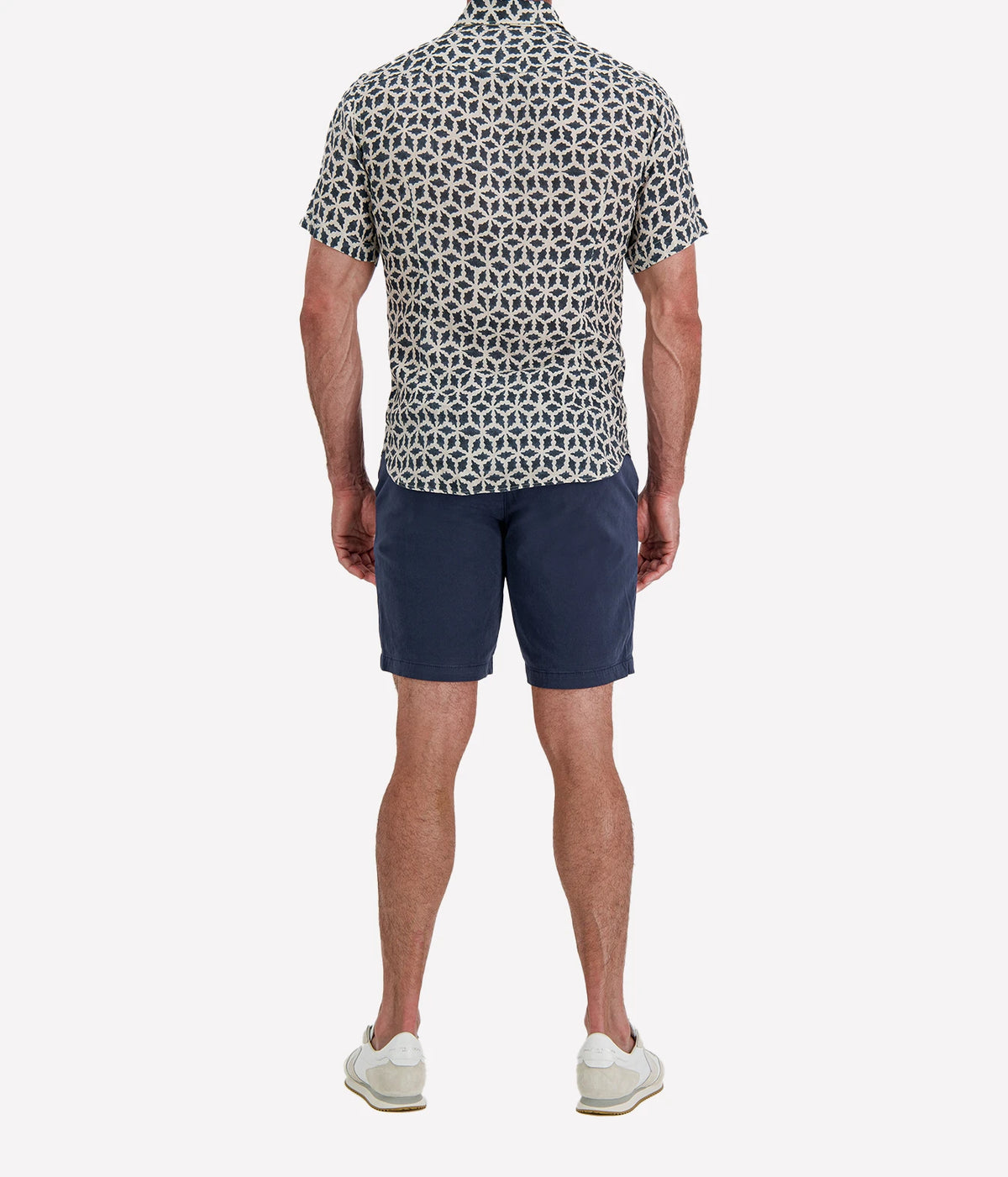 Back view of man wearing Osvaldo Trucchi Linen Short Sleeve Shirt in Navy Geo Star Print with navy shorts and white sneakers