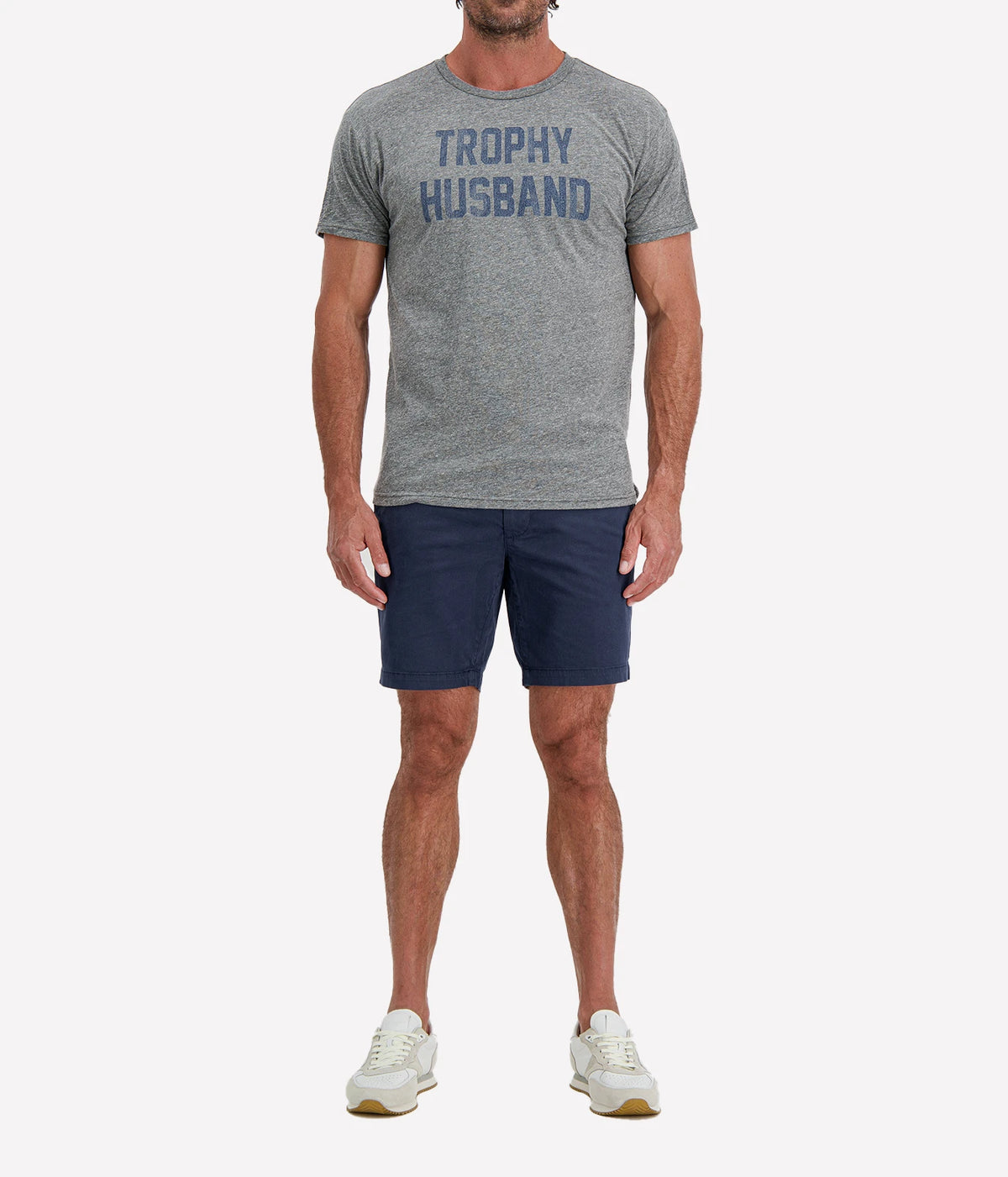 Man wearing Retro Brand Trophy Husband Tee in Grey & Navy with navy shorts and white sneakers, full-length front view