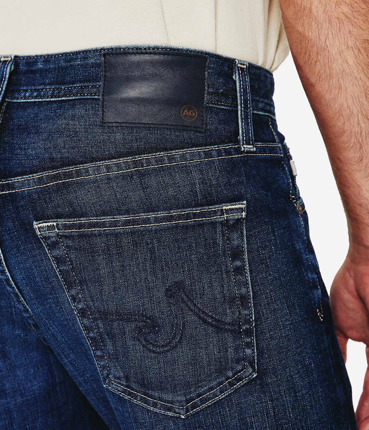 AG Graduate slim straight jeans for men in a medium-dark wash, featuring a slim mid-rise waist and relaxed fit through the hip to the knee. Tapered leg opening with Flex 360° Denim for added comfort and stretch