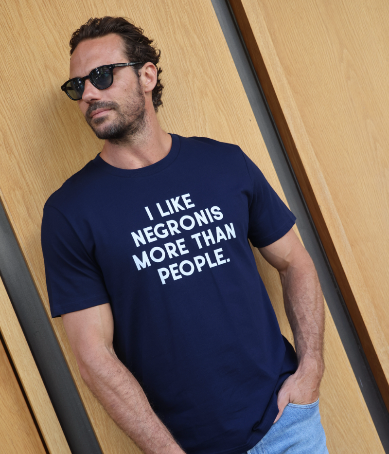 A model wearing the "I Like Negronis More Than People" graphic tee, styled effortlessly for a laid-back, witty look. Made from 100% organic cotton, this classic-fit shirt is the ultimate blend of comfort and personality.