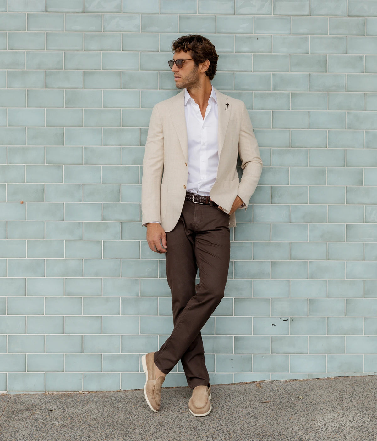 Man wearing Marco Pescarolo Neranom Cotton Five-Pocket Trouser in Grey with a cream blazer, white shirt and suede loafers, leaning against a tiled wall, full-length front view
