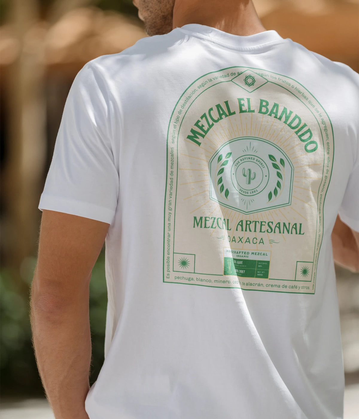 Man wearing The Refined Spirit Mezcal Tee in White outdoors, back view showing the back print