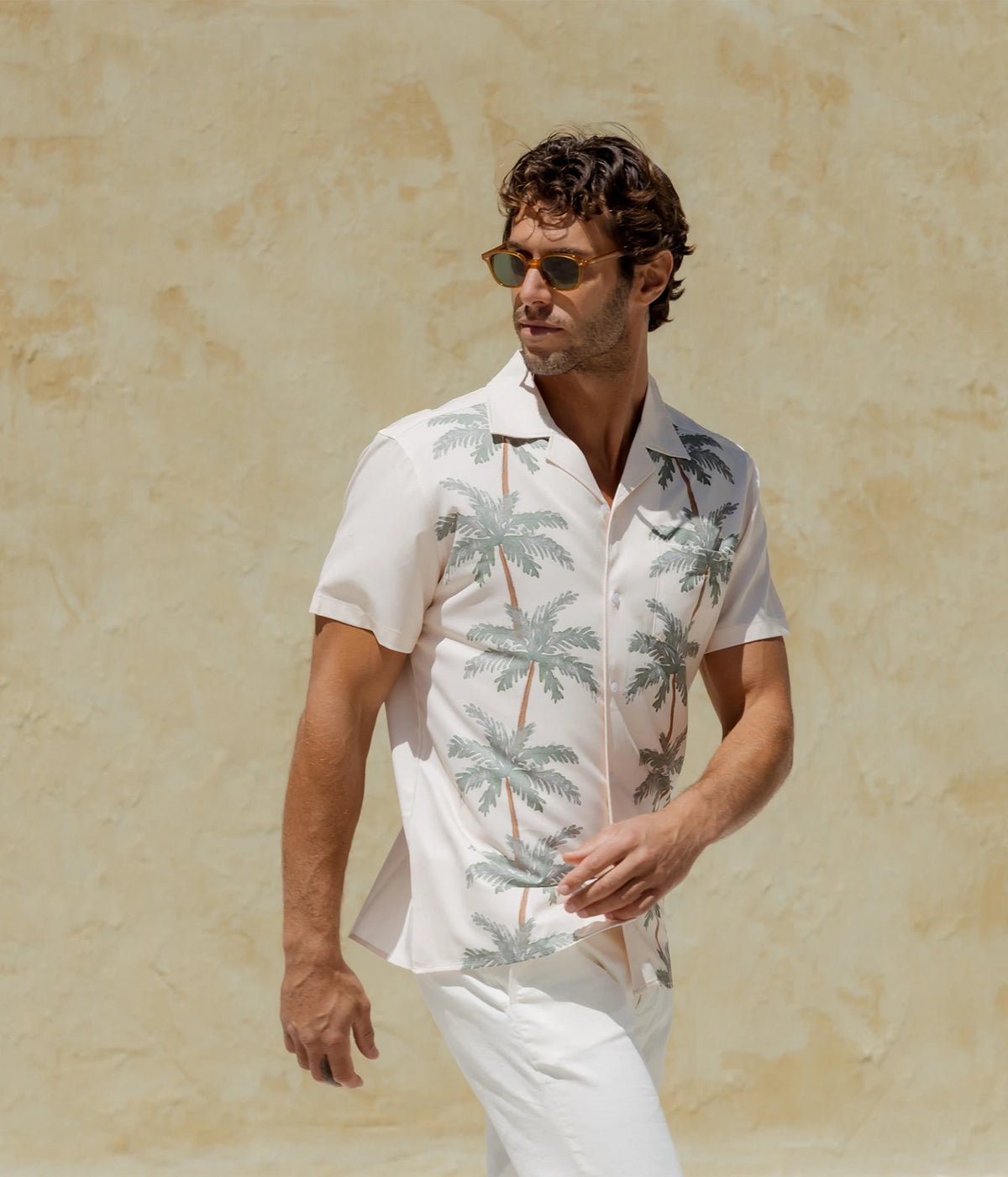 Man wearing Mavrans Palm Row Weekend Shirt in Light Green with white trousers and sunglasses, standing, front view