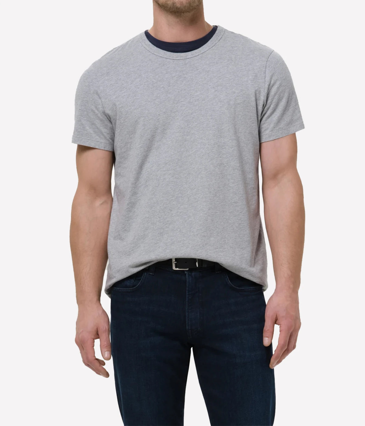 A man wearing a light grey short-sleeve t-shirt with a dark navy blue ribbed crew neck, paired with dark blue jeans, shown from the waist up against a light grey background.