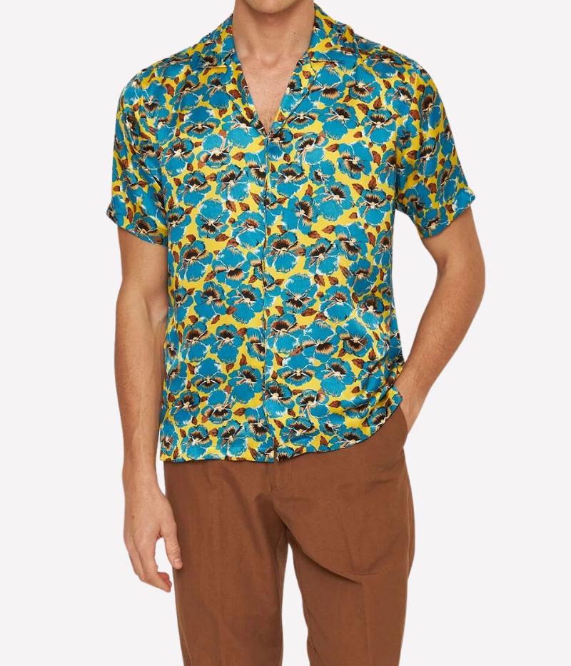 A vibrant silk shirt featuring an exclusive petal print in lemon yellow and blue, a relaxed fit, Capri collar, concealed front placket, and branded imitation mother-of-pearl buttons. Made in Portugal from 100% GOTS-certified silk.