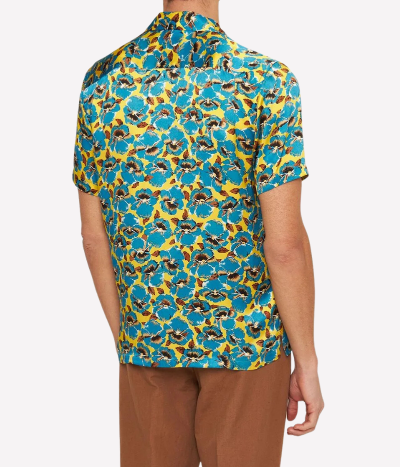 A vibrant silk shirt featuring an exclusive petal print in lemon yellow and blue, a relaxed fit, Capri collar, concealed front placket, and branded imitation mother-of-pearl buttons. Made in Portugal from 100% GOTS-certified silk.