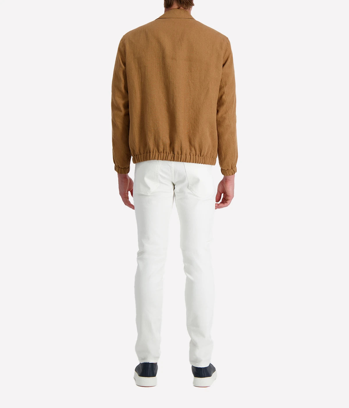 Man wearing a tan Lardini linen jacket with a zip front, elasticated hem and cuffs, and a shirt collar, styled with a white tee and white trousers.