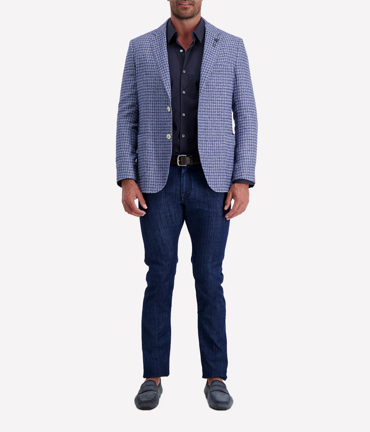 Man wearing a Lardini blue herringbone blazer with a relaxed fit, paired with a cream polo shirt and off-white trousers. The lightweight flax-wool blend fabric drapes effortlessly, featuring a subtle texture and classic herringbone pattern. Styled with sunglasses and an open collar, the look exudes effortless sophistication.