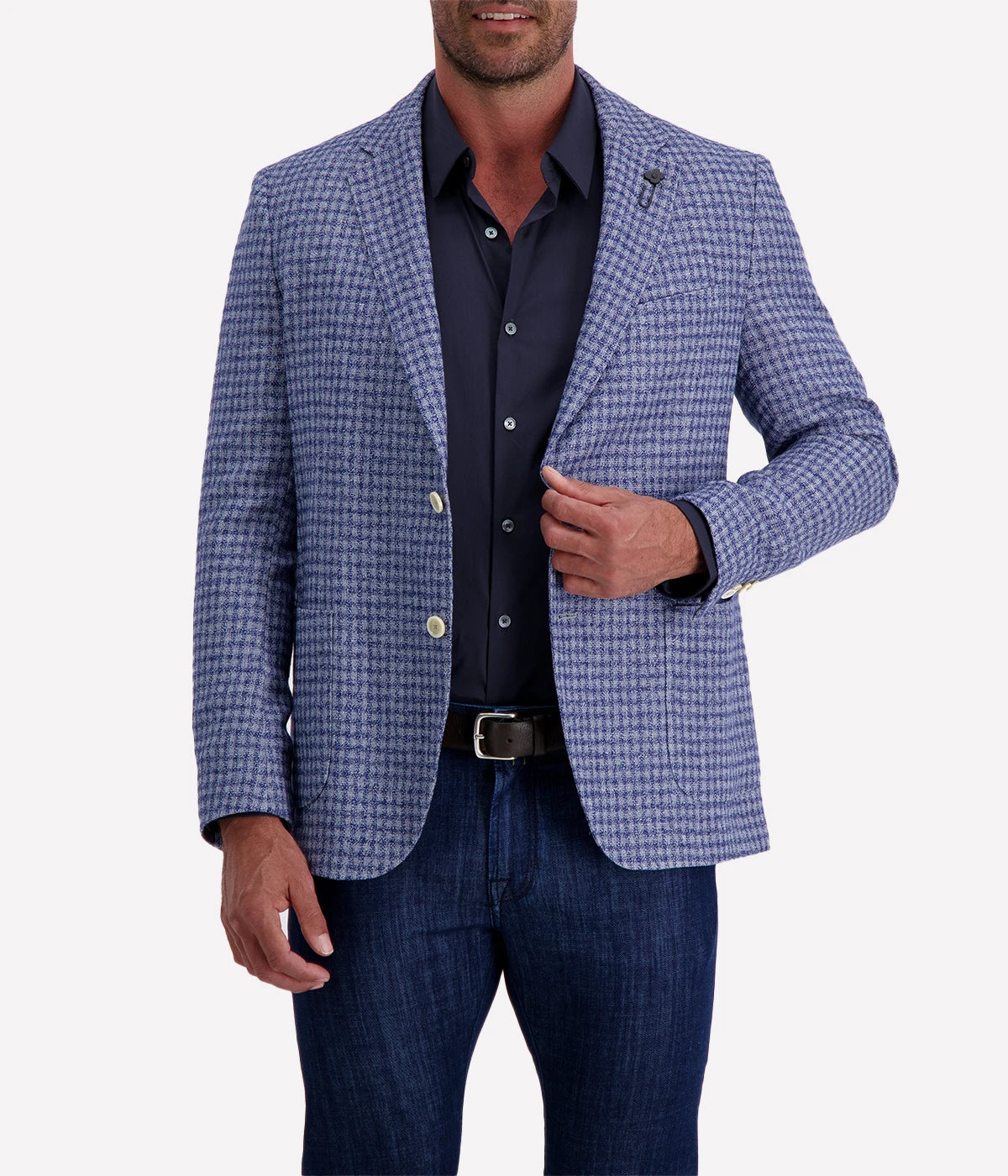 Man wearing a Lardini blue herringbone blazer with a relaxed fit, paired with a cream polo shirt and off-white trousers. The lightweight flax-wool blend fabric drapes effortlessly, featuring a subtle texture and classic herringbone pattern. Styled with sunglasses and an open collar, the look exudes effortless sophistication.