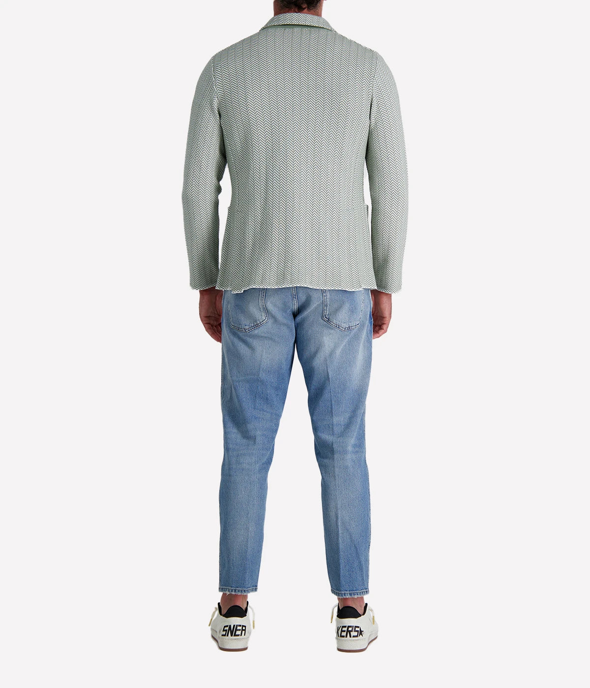 A green and white Lardini knit jacket with a herringbone pattern, soft unstructured fit, and signature floral lapel pin, made from 100% cotton, styled with a white t-shirt and jeans.