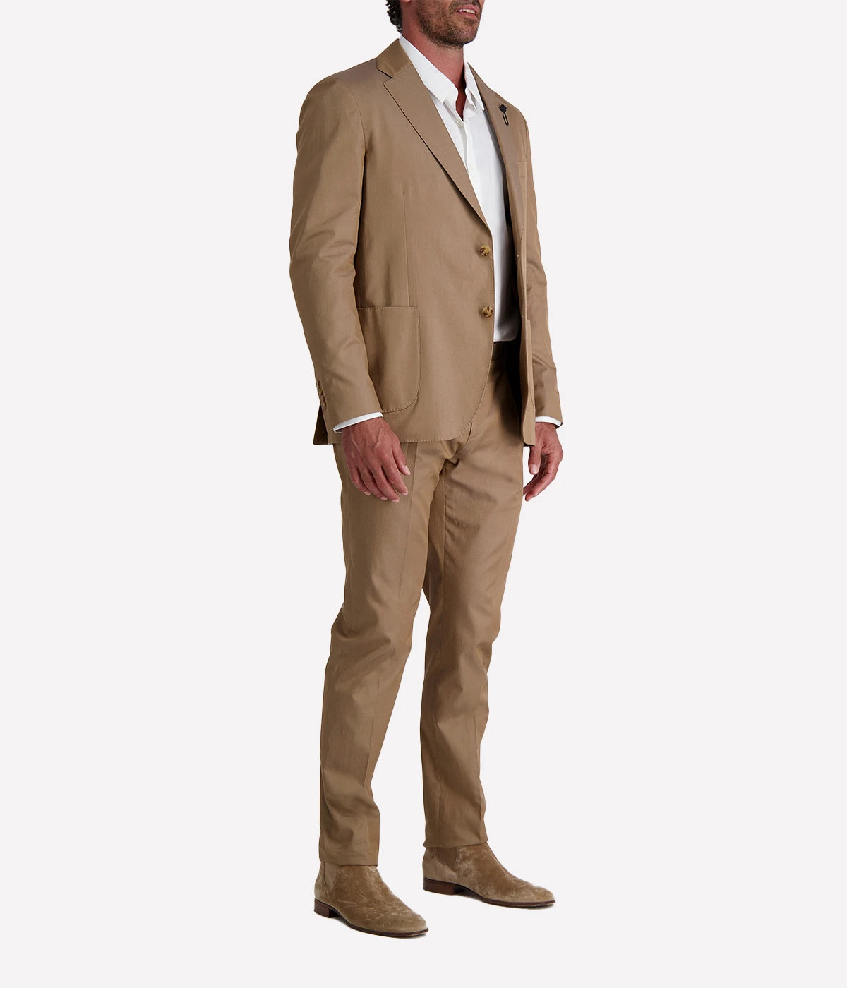 Model wearing a light brown Lardini cotton suit with a white shirt and suede loafers, featuring a single-breasted blazer with Lardini’s signature boutonnière, styled outdoors in a relaxed, modern setting.