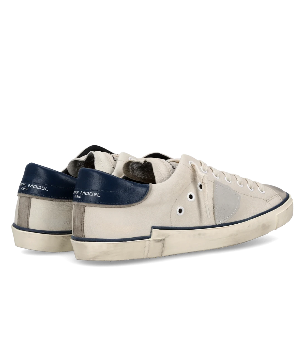 Rear three-quarter view of the Philippe Model Prsx Low Man in Vintage Bordure Lait Bleu pair, showing the navy heel tabs and worn-in vintage sole