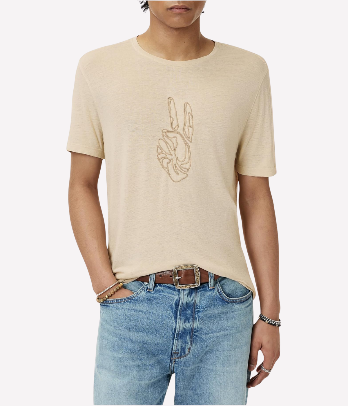 Person wearing a beige t-shirt with a peace sign design and light blue jeans on a white background