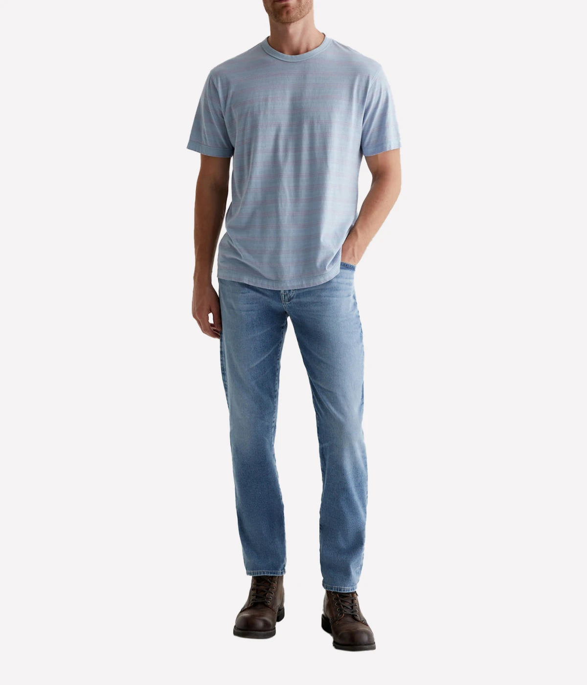 Model wearing the Tellis Modern Slim Jean in light blue wash with AG-ed™ details, paired with a casual tee for an effortless yet stylish everyday look. The jeans' velvety feel and tapered leg offer both comfort and a flattering fit.