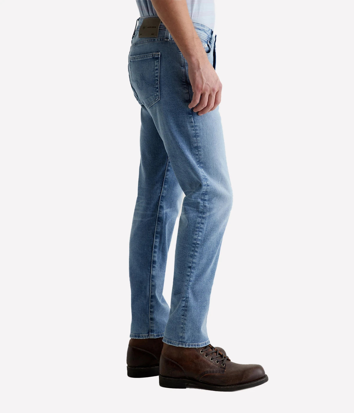 Side view of the Tellis Modern Slim Jean on a model, showcasing the fitted upper block and tapered leg opening. The light blue wash with AG-ed™ fading adds a timeless, lived-in feel to the modern slim fit.