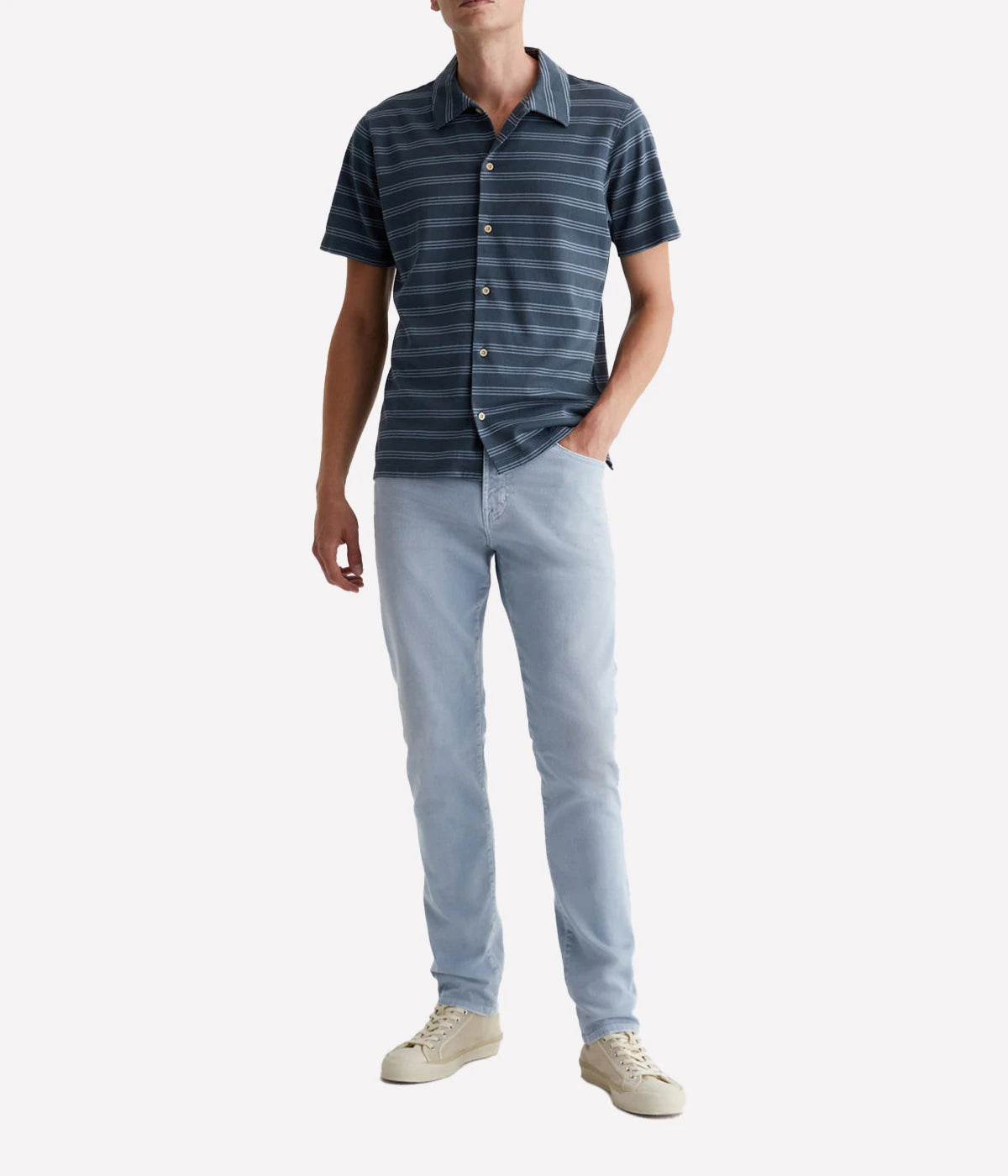 Model wearing the Tellis Modern Slim Jean in light blue wash, styled with a casual shirt for a relaxed yet stylish look. The AG-ed™ fading, whiskering, and distressed edges give the jeans a timeless, lived-in vibe, while the supple feel ensures ultimate comfort.