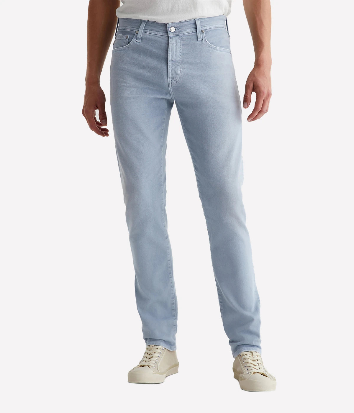 AG Tellis Modern Slim Jean in a light blue wash, featuring fading, whiskering, and worn edges that replicate 19 years of wear. The jeans are designed with a fitted upper block and a tapered leg opening for a slim, flattering fit.