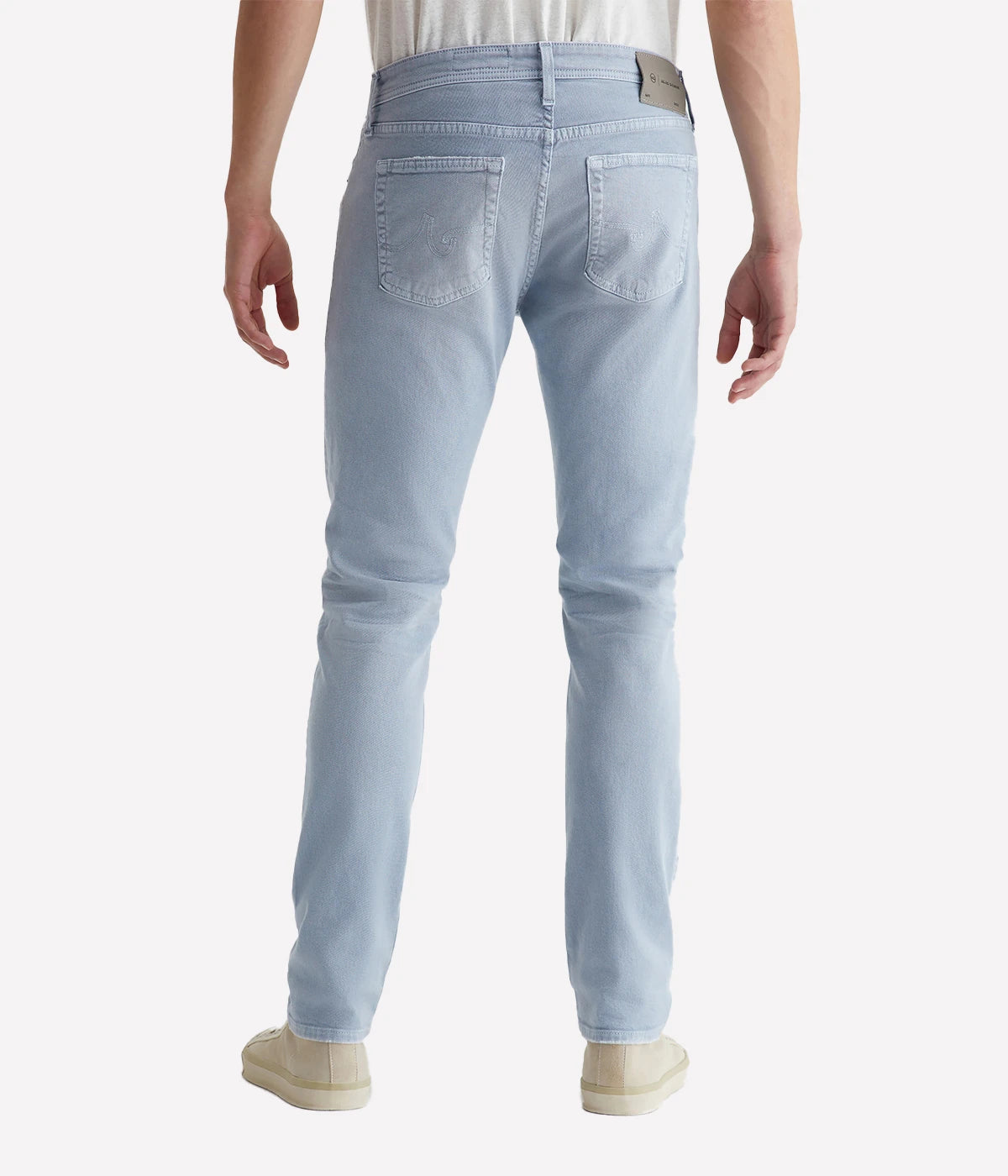 Back view of the Tellis Modern Slim Jean in light blue wash, showcasing the tailored fit and worn-in details like fading and whiskering that mimic 19 years of wear. The tapered leg opening offers a modern, slim silhouette.