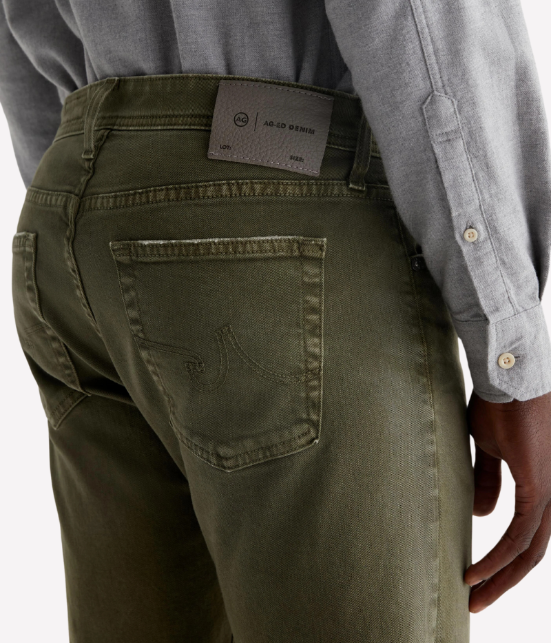 The Tellis jean in sulfur-dyed grass green features a modern slim fit with a mid-rise waist and tapered leg. Crafted from Hyper Soft Bull Denim with AG Cloud Soft Denim™ for a luxuriously soft feel and enhanced stretch.