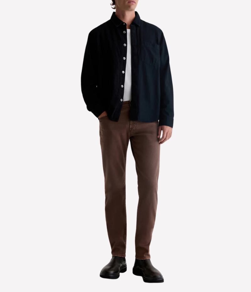 Model wearing the AG Tellis Slim Fit jeans in 7 Years Sulfur Berry Brown, styled with a jacket for a smart yet laid-back look. The sulphur-dyed brown shade and AG-ed™ finish deliver a vintage charm, while the Cloud Soft Denim™ ensures lasting comfort and softness.