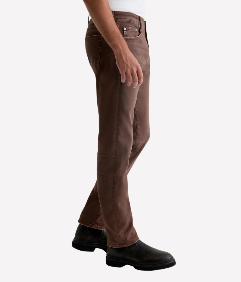 Side view of the AG Tellis Slim Fit in Sulfur Berry Brown, highlighting the slim, tapered leg and mid-rise waist. The AG-ed™ finish and soft Cloud Soft Denim™ construction provide a stylish yet comfortable look with a sleek silhouette.