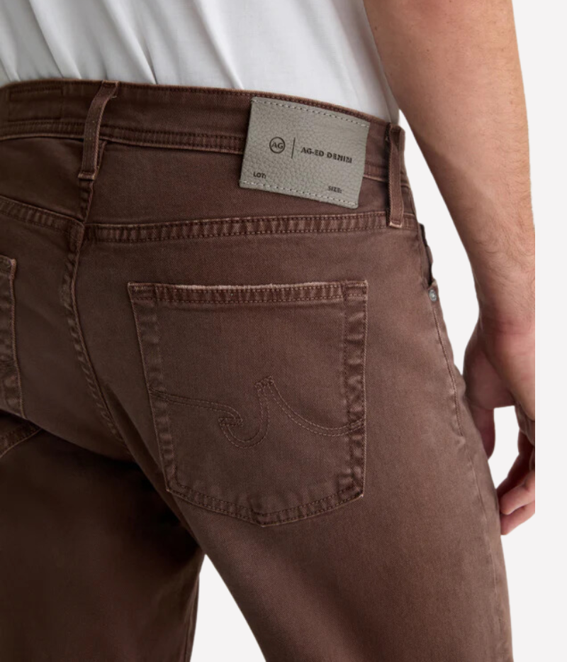 Close-up of the 7 Years Sulfur Berry Brown AG Tellis Slim Fit jeans, showcasing the unique sulphur-dyed finish, fading, and wear marks for an authentic, vintage look. Crafted from AG Cloud Soft Denim™, the fabric’s soft texture is enhanced with dual-elastic performance fibres for stretch and comfort.