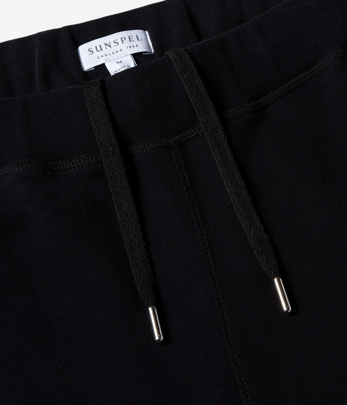 Men’s slim fit track pants in black, crafted from loopback cotton with ribbed waistband and tapered leg—part of a matching track set.