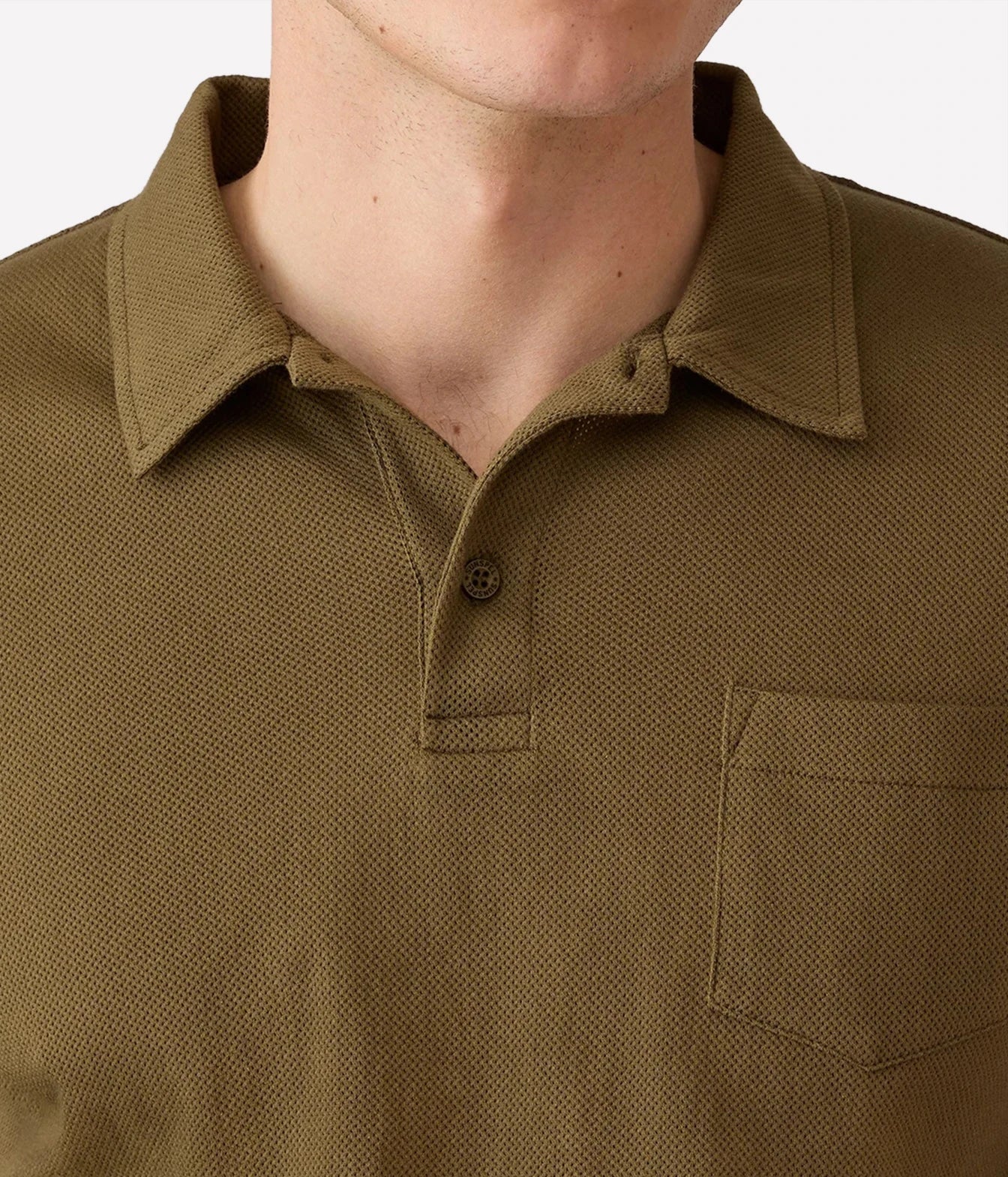 Close-up of a man wearing a textured polo shirt in olive green, showing the collar, button placket, and chest pocket.