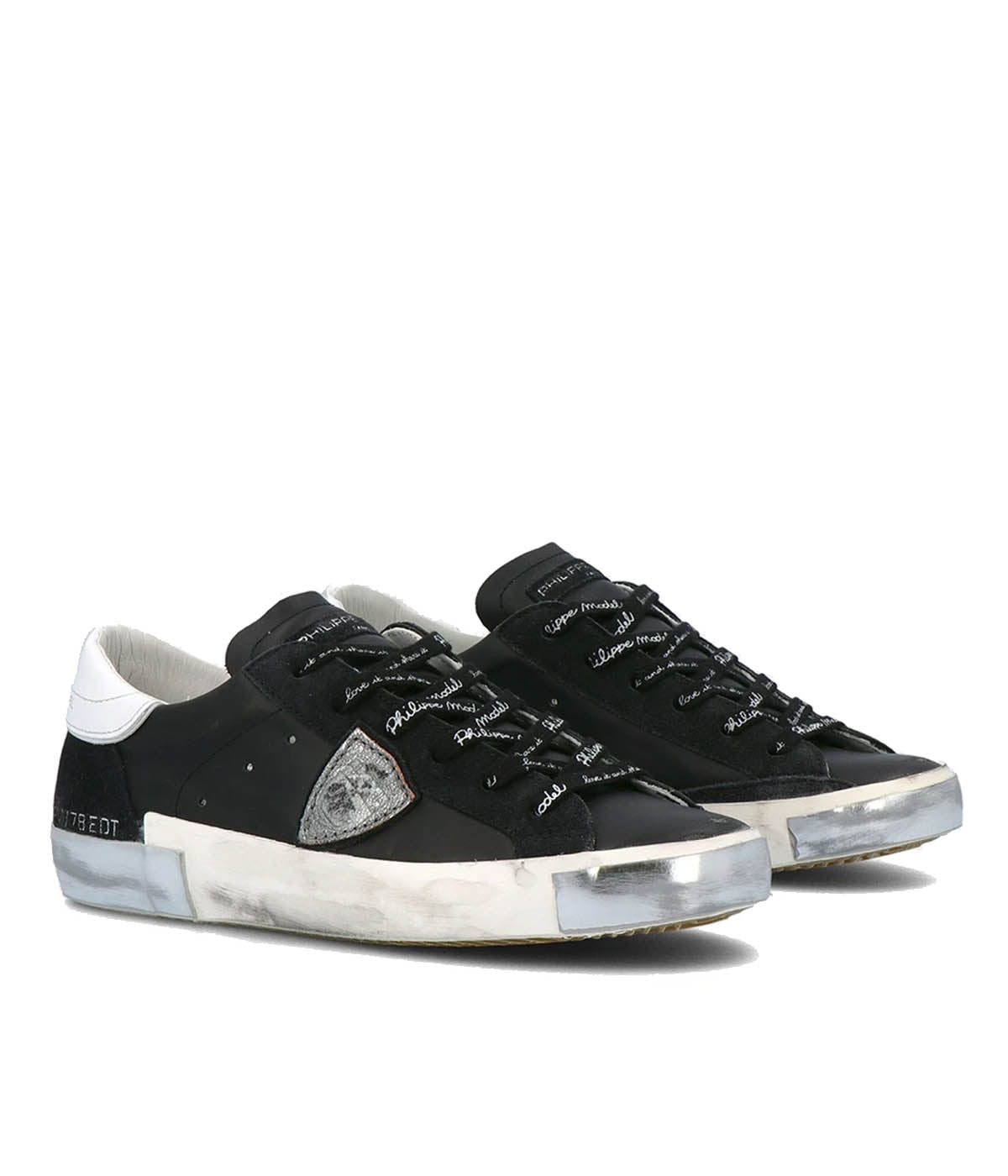 Angle view of Philippe Model PRSX Low Man sneakers, emphasizing the shield on the side of the shoe with the City of Paris coat of arms. The calfskin and suede upper has a worn, vintage-used effect, and the screen-printed laces add to the sneakers' timeless appeal.