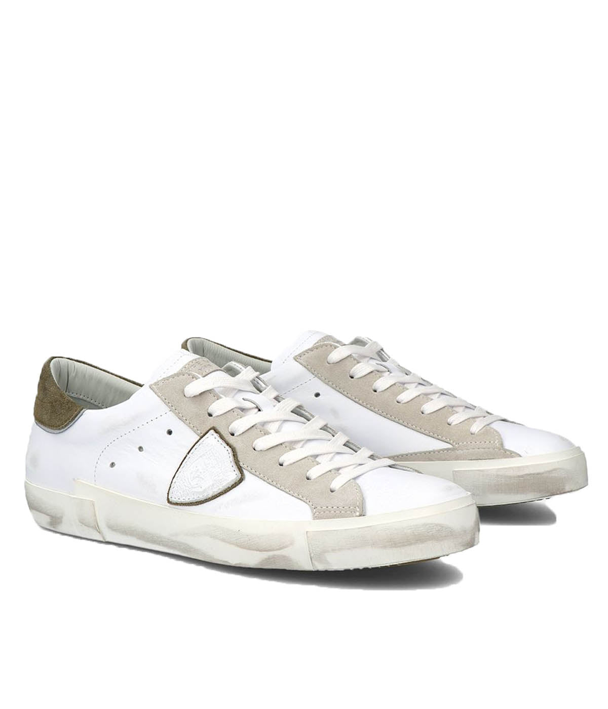 Angle view of Philippe Model PRSX Low Man sneakers, emphasizing the shield on the side of the shoe with the City of Paris coat of arms. The calfskin and suede upper has a worn, vintage-used effect, and the screen-printed laces add to the sneakers' timeless appeal.