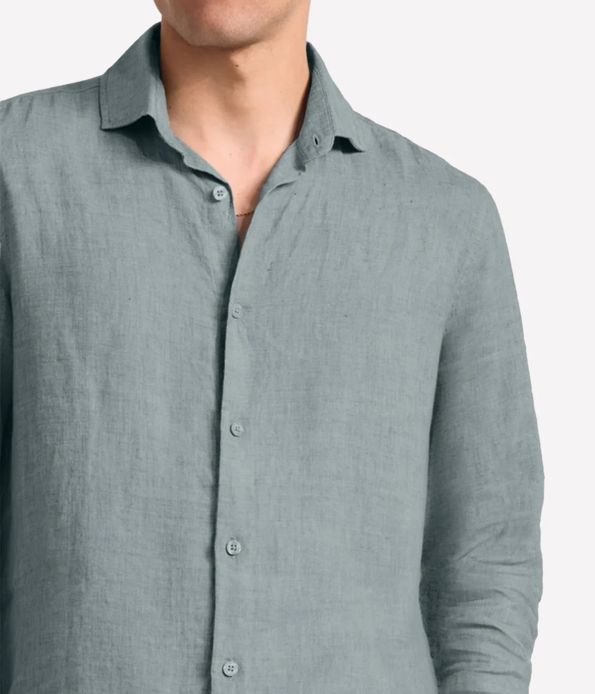 A close-up of a man wearing a Frescobol Carioca Antonio Linen Long Sleeve Shirt in Ash Green, showing the collar, front buttons, and textured fabric against a light grey background.
