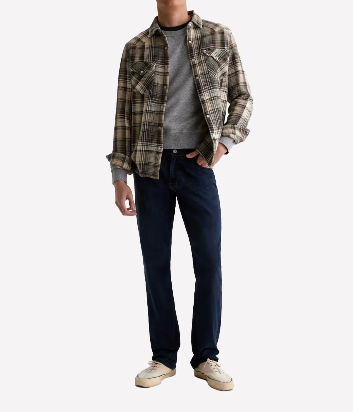 Man wearing AG Graduate Jean in Studio with a check overshirt, charcoal tee and cream sneakers, front view